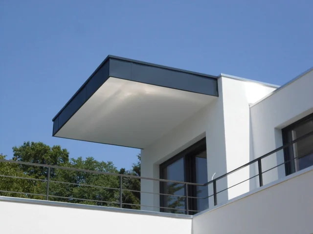 Moderne weiße Gebäudefassade mit Balkon und großen Fenstern unter blauem Himmel.